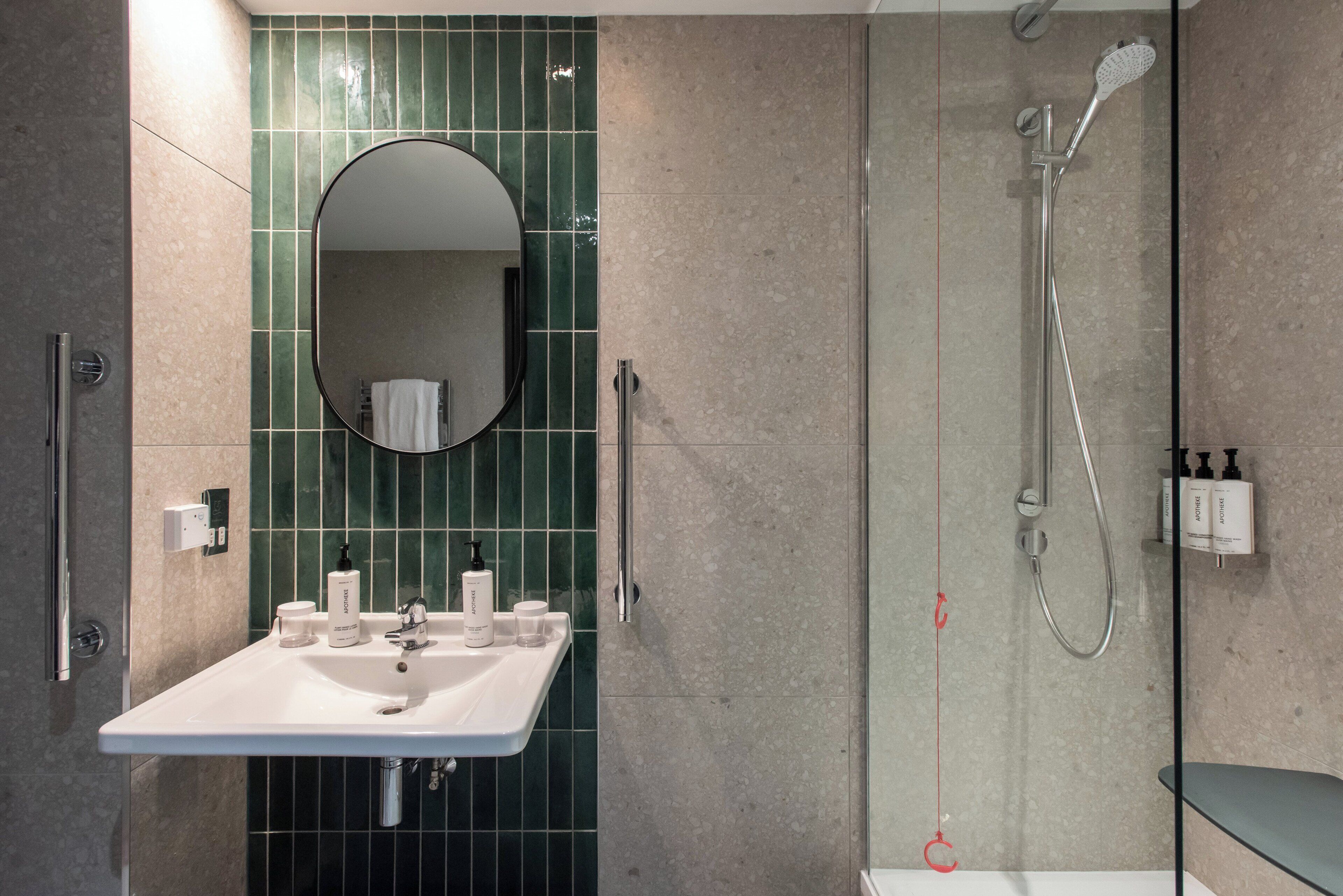 A modern bathroom with a white sink, mirror, and shower.
