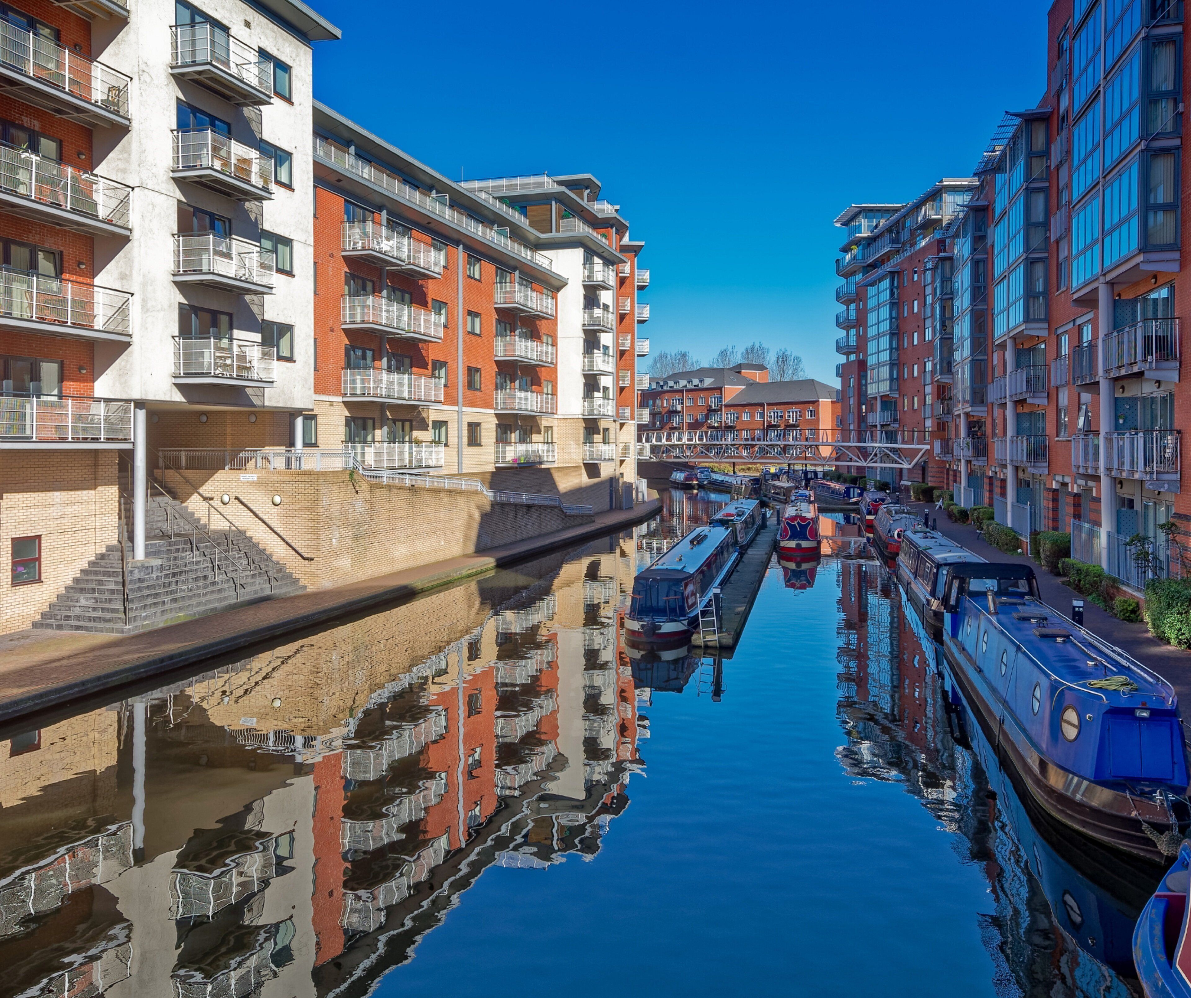 A canal with boats, surrounded by multi-story residential buildings with balconies.