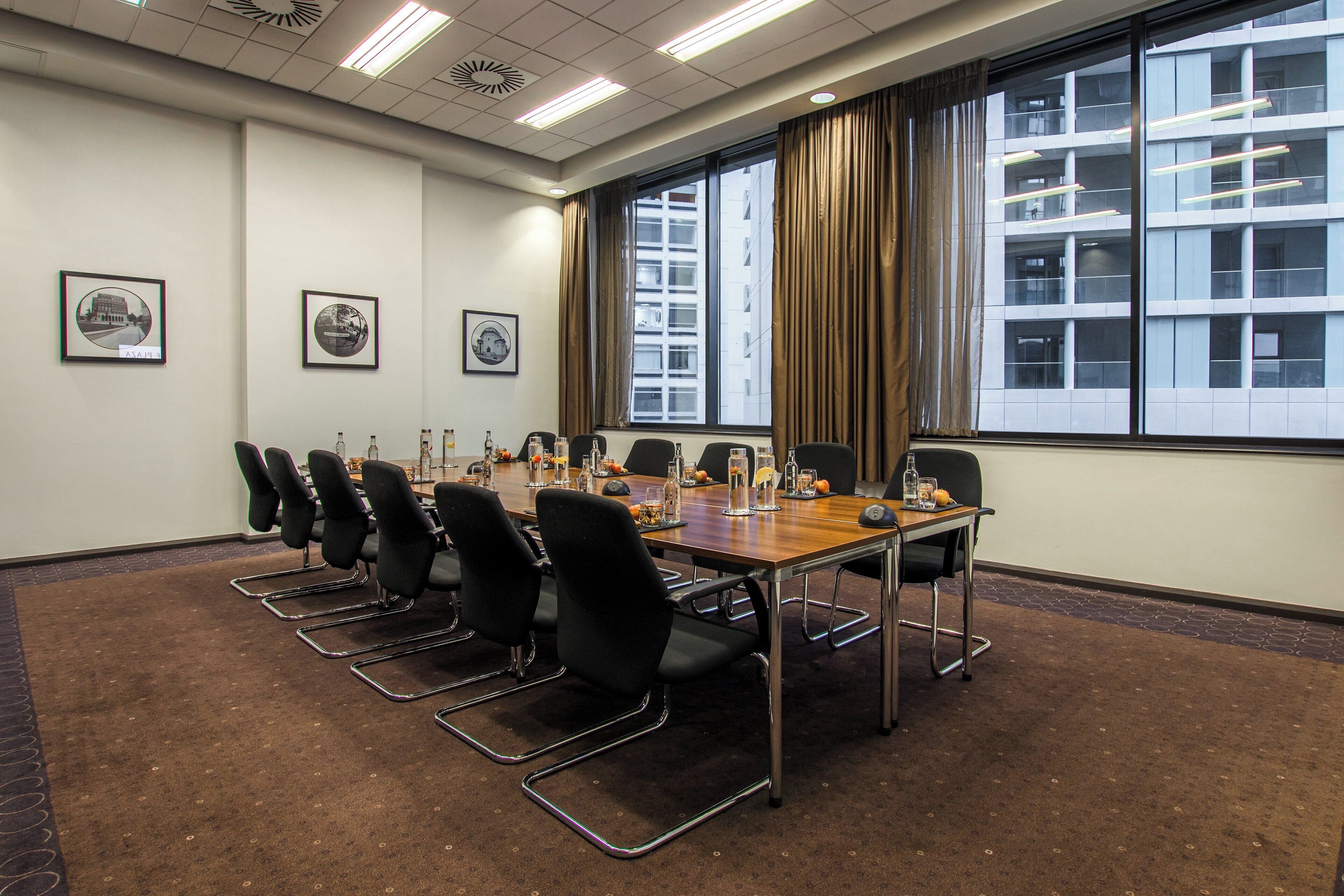 A conference room with a long table, chairs, and framed pictures on the wall.