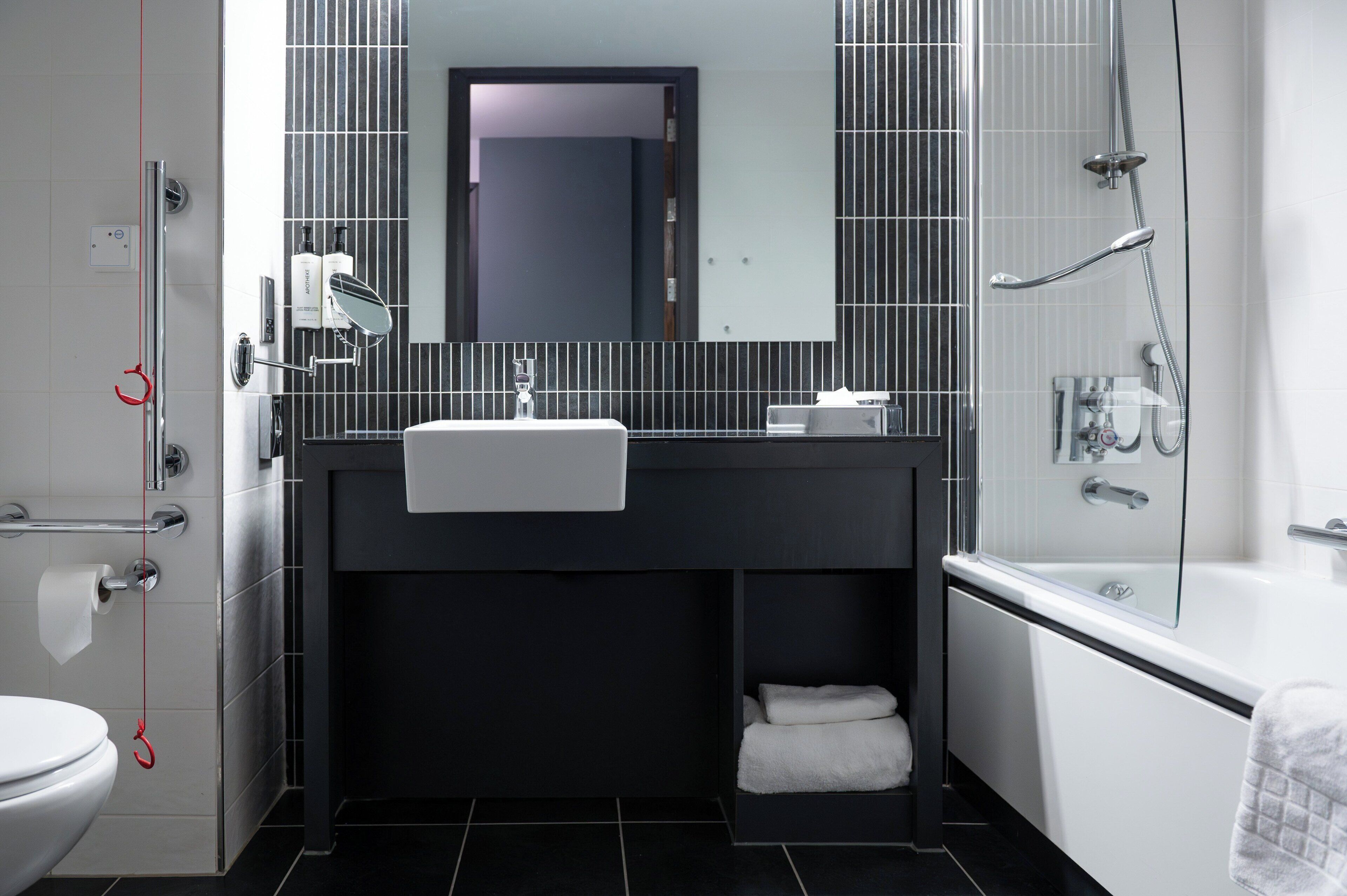 A modern bathroom with a black sink, white toilet, and a glass-enclosed shower.