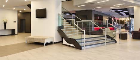 Un vestíbulo moderno con una escalera, un mostrador de recepción y una zona de estar.