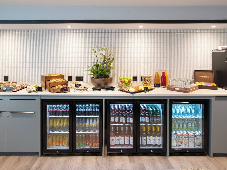 A self-service breakfast bar with various food items, a coffee machine, and beverage dispensers.