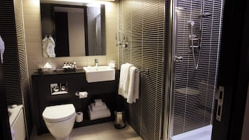 Une salle de bain moderne équipée de toilettes, d’un lavabo, d’un miroir et d’un espace douche.