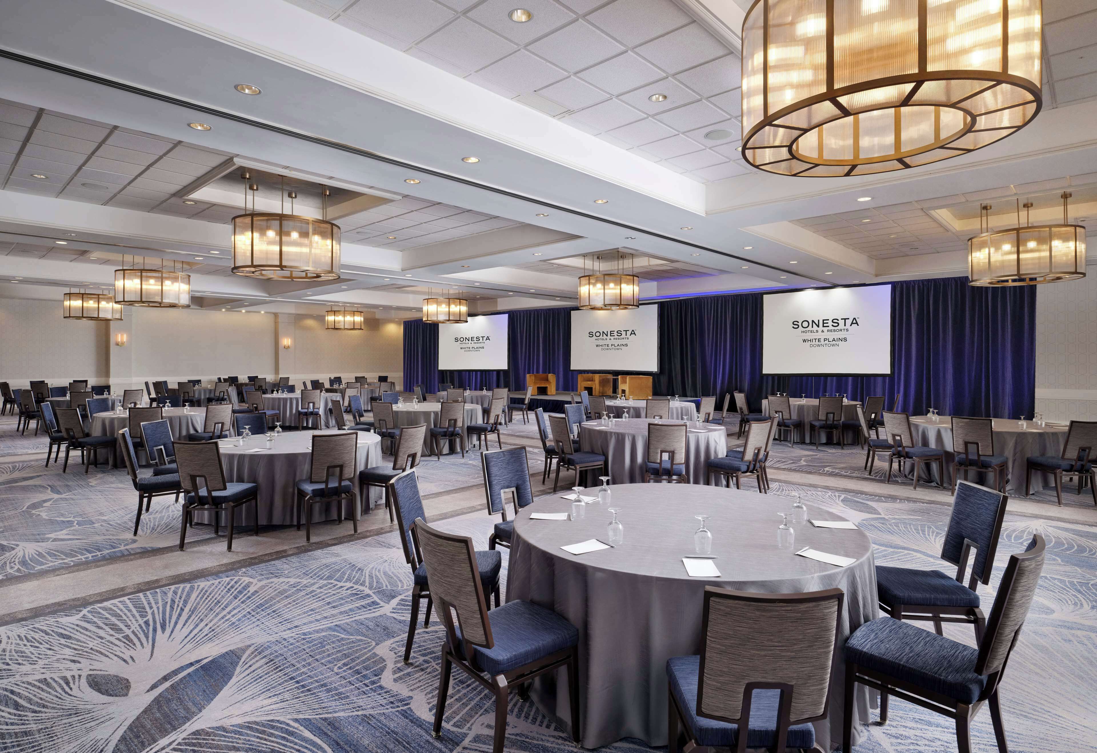 A conference room with round tables and chairs, banners, and a carpeted floor.