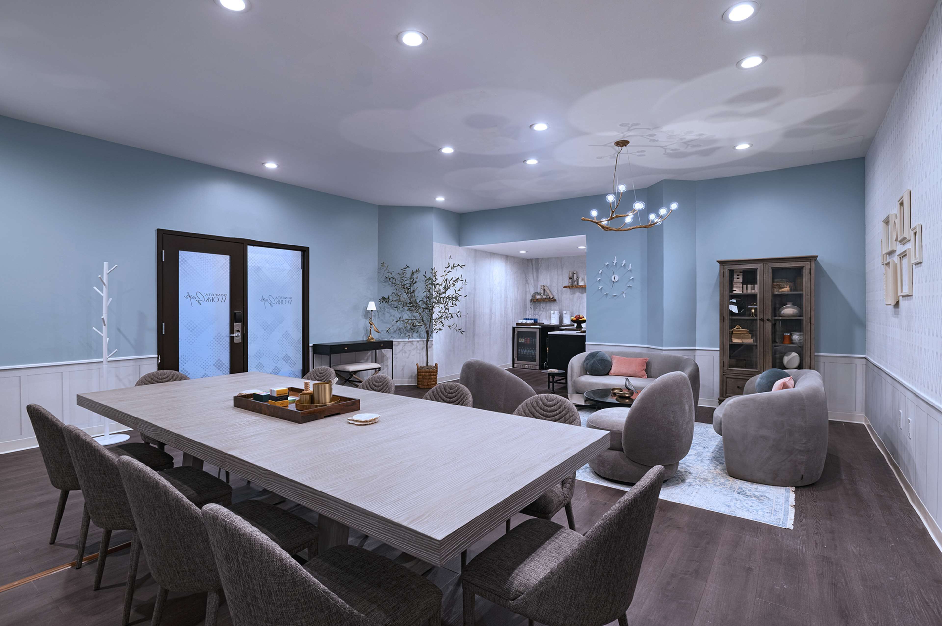 Une salle de réunion moderne, dotée d’une grande table, de sièges confortables et d’un lustre décoratif.