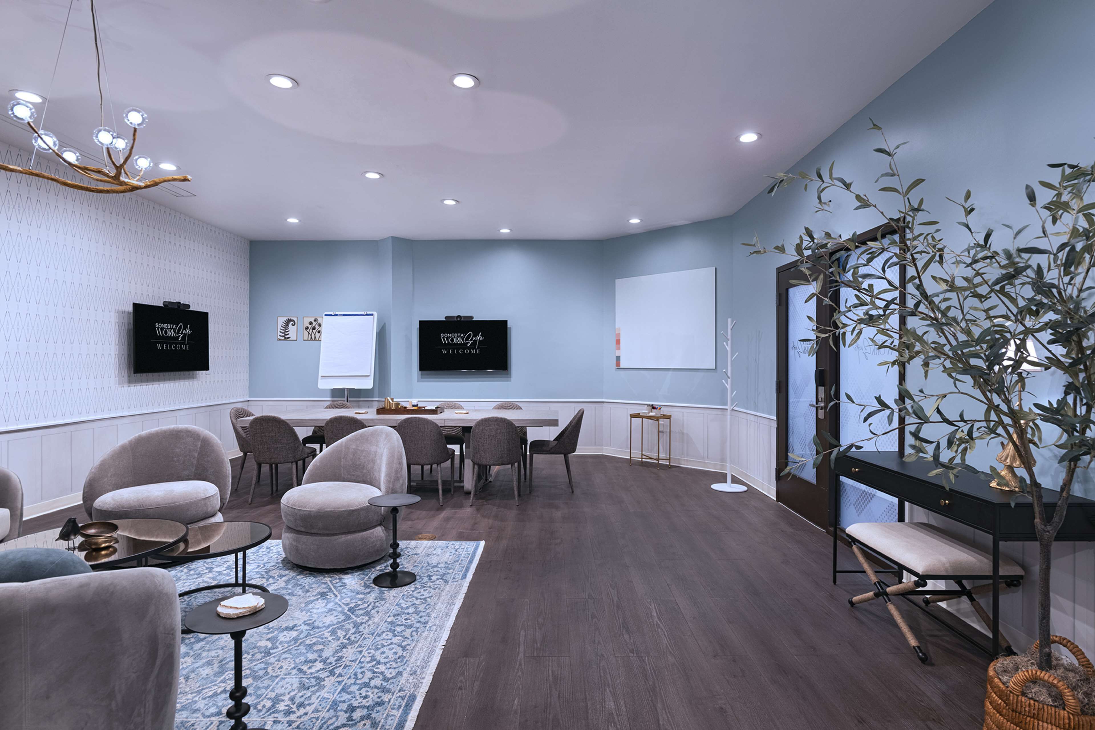 A modern conference room with a round table, comfortable seating, and a large screen.