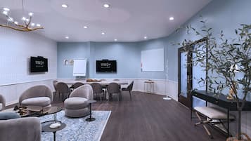 A modern conference room with a round table, comfortable seating, and a large screen.