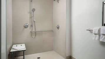 Uma área de chuveiro moderna, com chuveiro manual, chuveiro fixo e box envidraçado.