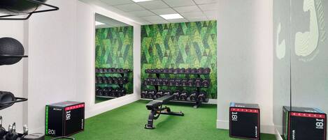 A gym with green artificial turf, weight racks, and exercise equipment.