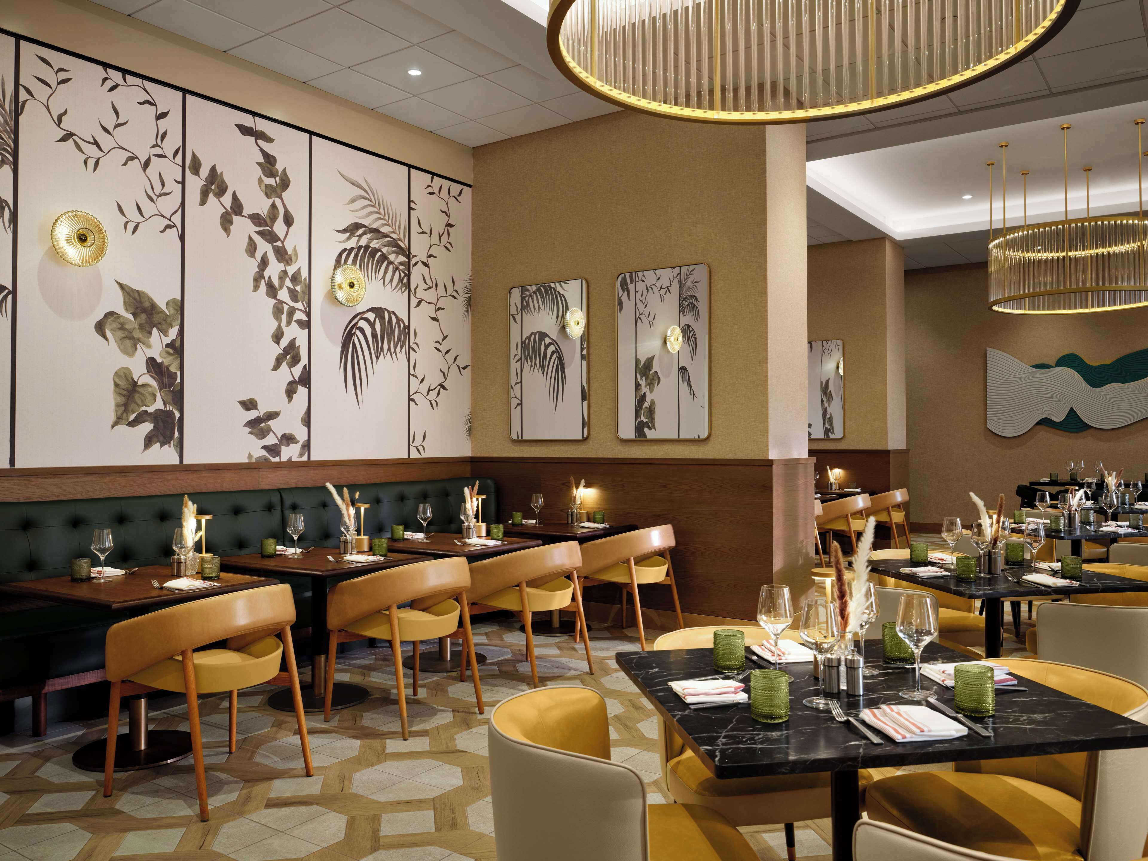 Un restaurante con varias mesas y sillas, un muro con diseño y una lámpara moderna.