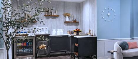 Una cocina moderna con armarios oscuros, refrigerador empotrado y una estación para café.