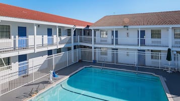 Un hotel con piscina, balcones y tejado de tejas rojas.