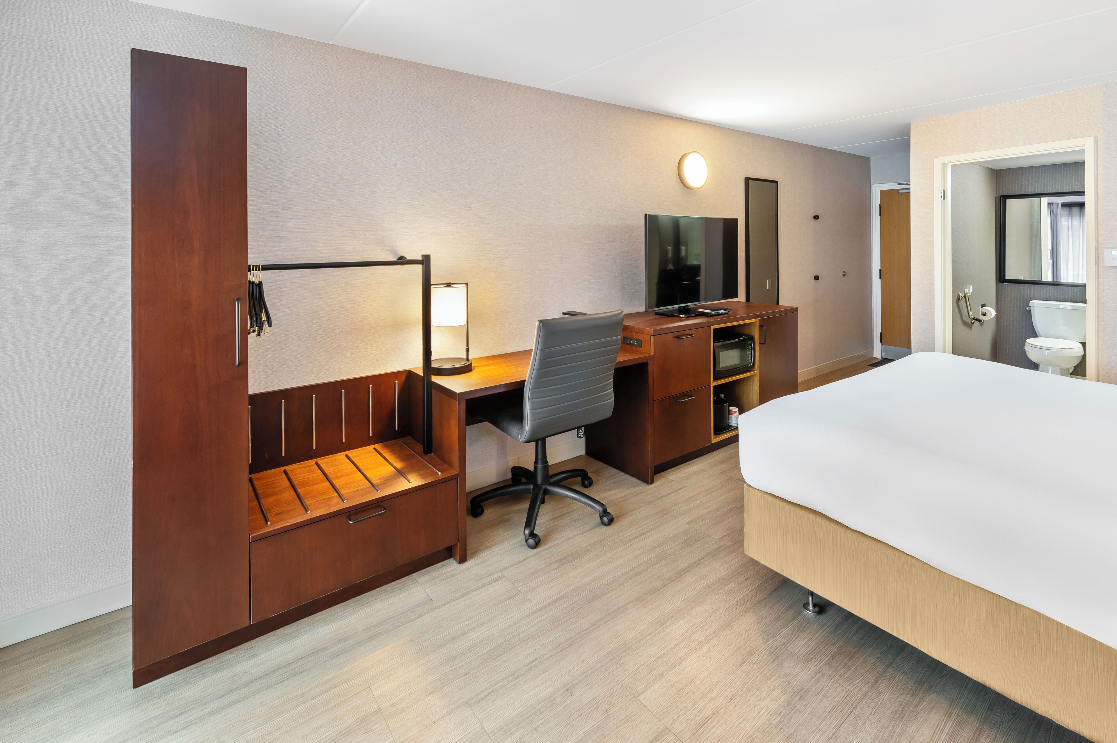 Une chambre d’hôtel comprenant un lit, un bureau avec une chaise, une télévision, une armoire et une salle de bain.