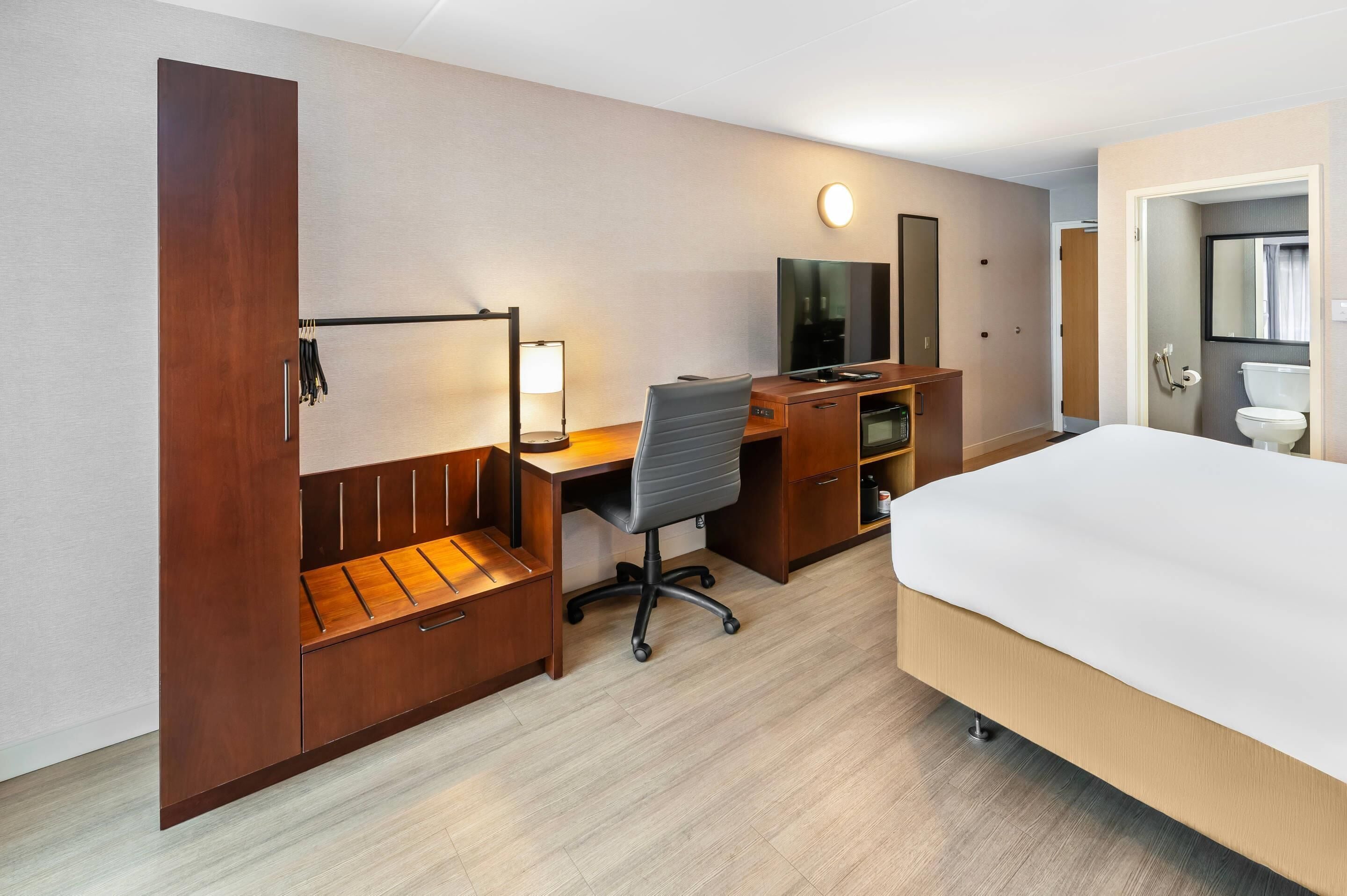 Une chambre d’hôtel équipée d’un lit, d’un bureau, d’une chaise, d’une armoire et d’un téléviseur.