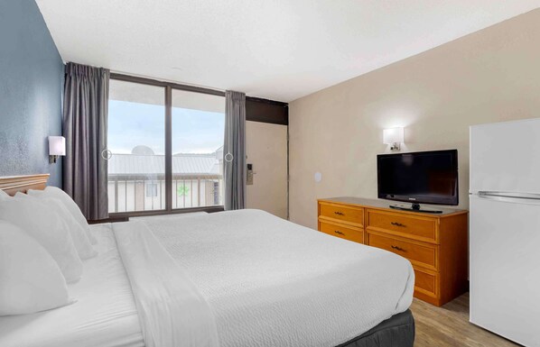 A hotel room with a large bed, a television, a dresser, and a refrigerator. - Extended Stay America Suites - Bristol (Bristol)