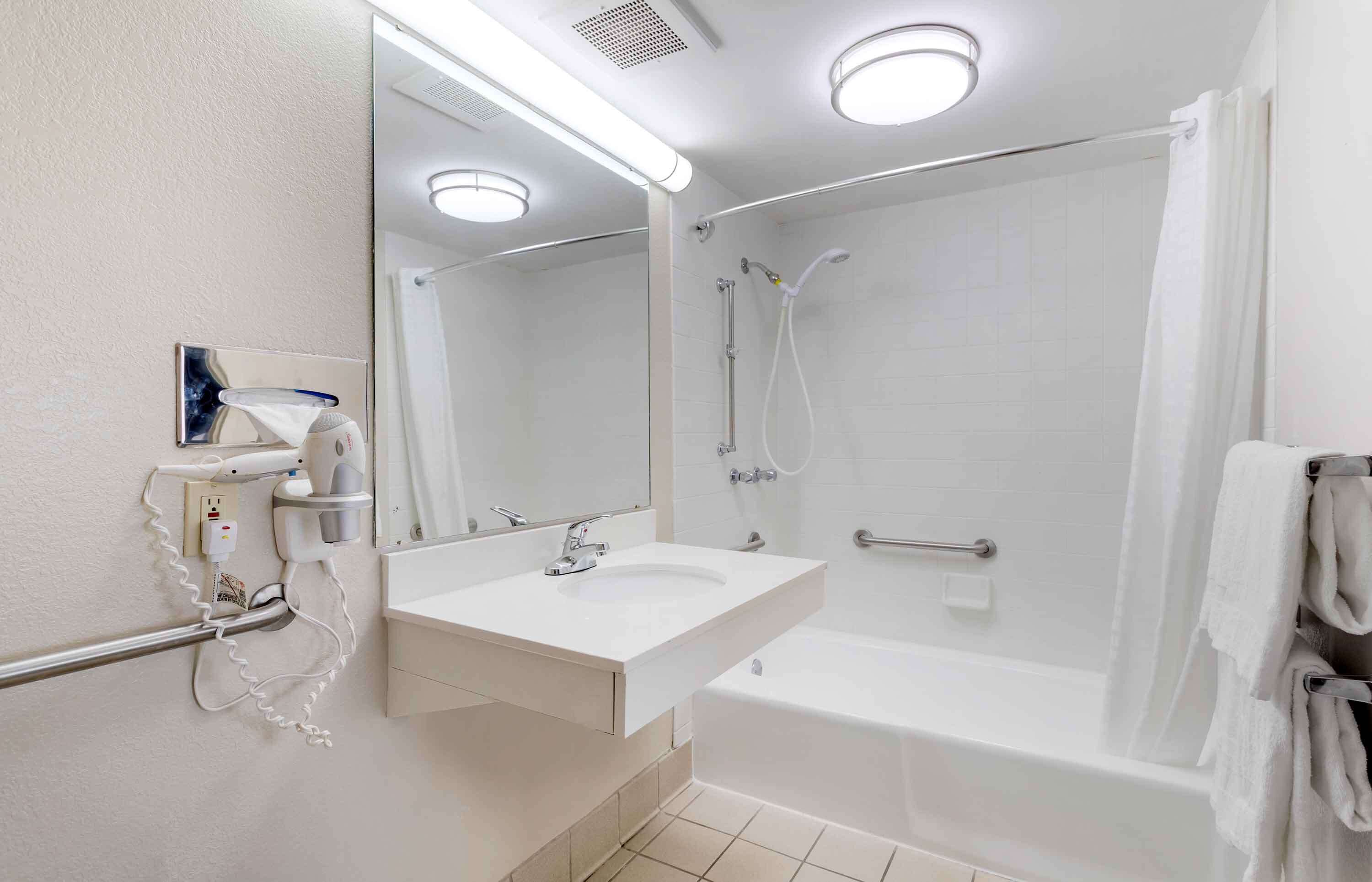 A modern bathroom with a white sink, mirror, and shower.