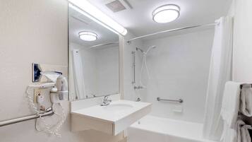 A modern bathroom with a white sink, mirror, and shower.