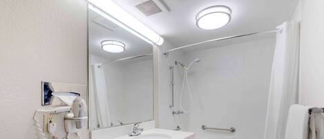 A modern bathroom with a white sink, mirror, and shower.