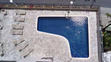 Una piscina al aire libre, sillones reclinables de piscina