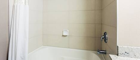 A bathroom with a bathtub, a showerhead, and a soap dish.