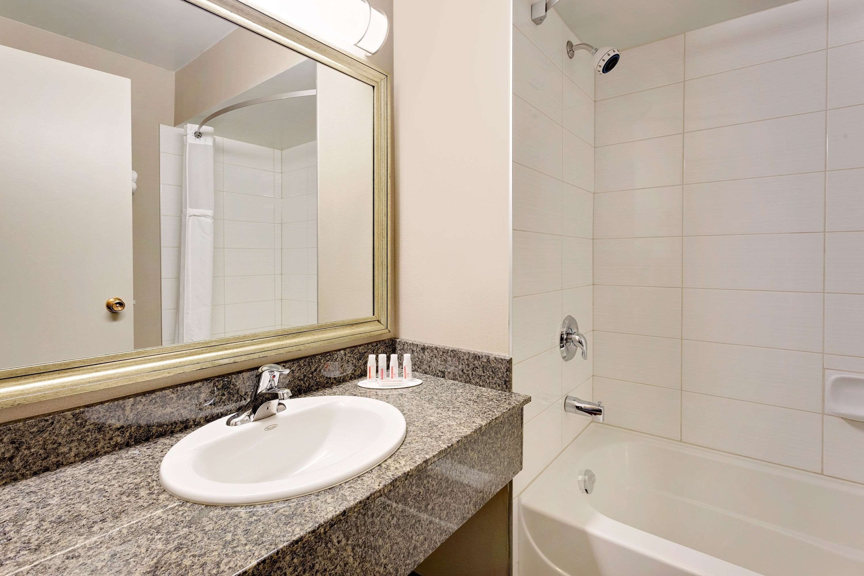 A bathroom with a white sink, a large mirror, and a bathtub.