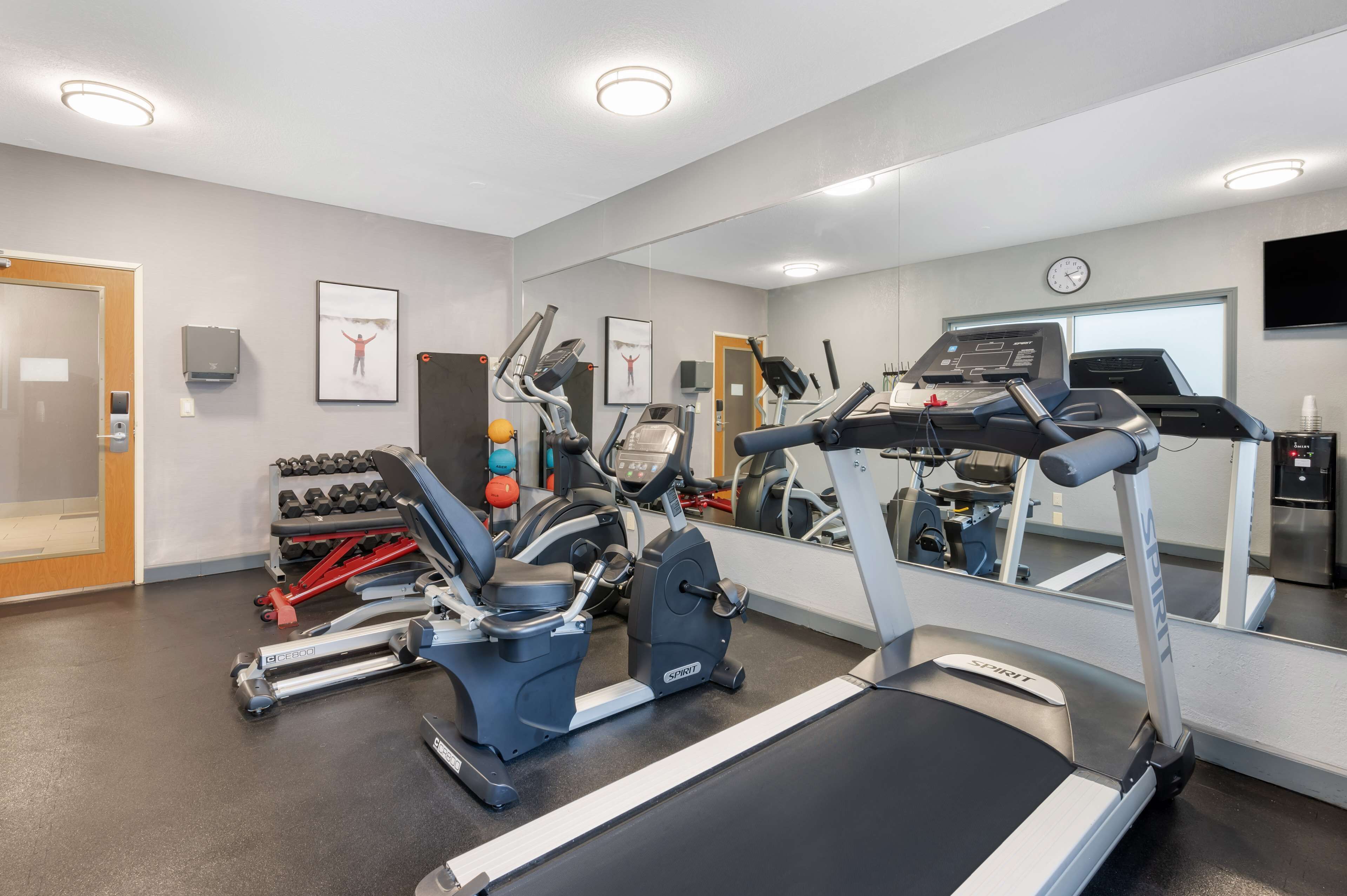 Een fitnessruimte met loopbanden, elliptische trainers en losse gewichten.