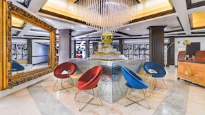 A lobby with a chandelier, a large mirror, and a central decorative structure. - Chateau Mar Golf Resort, Trademark Collection by Wyndham (Lauderhill)