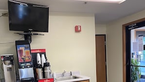 A kitchenette area with a coffee machine, a small refrigerator, and a flat-screen TV mounted above the counter. - Americas Best Value Inn Champaign (Champaign)