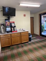 Una zona de kitchenette con cafetera, un refrigerador pequeño y un televisor de pantalla plana sobre la encimera.