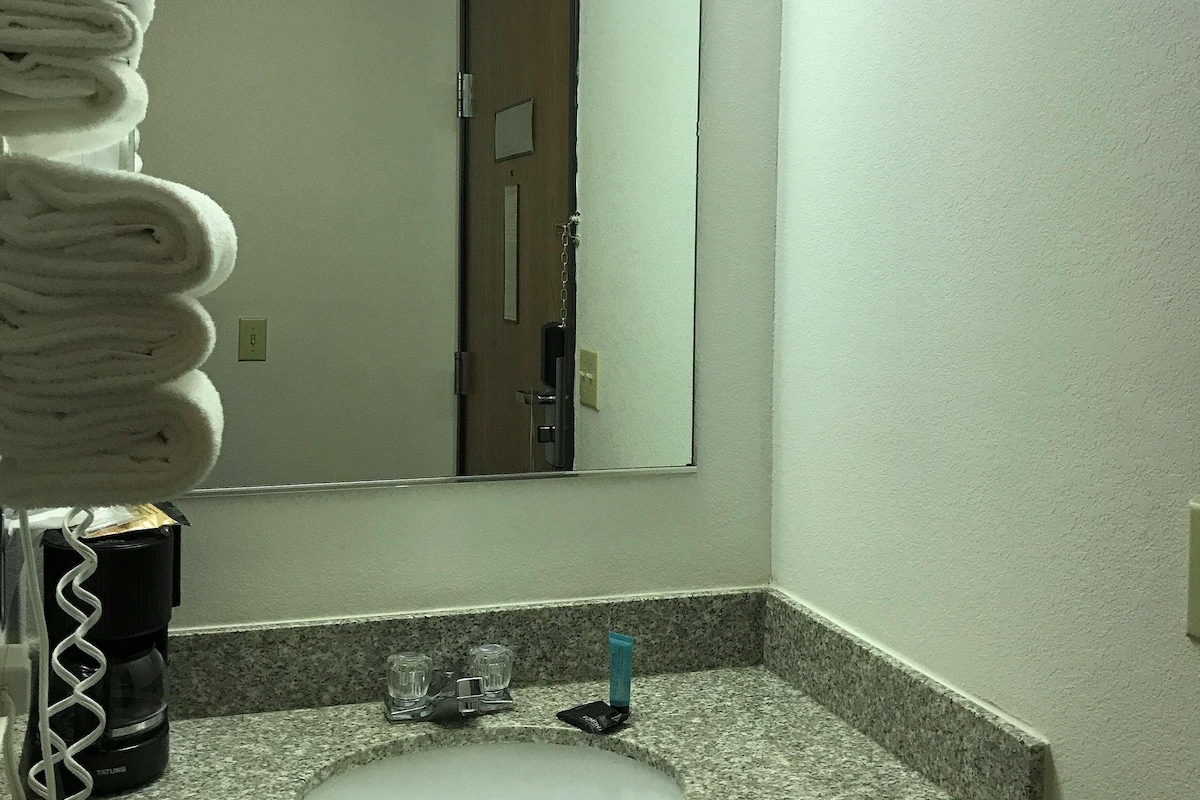 A bathroom with a granite countertop, a sink, a mirror, and a towel rack with towels.