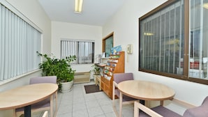 A reception area with two round tables, chairs, a potted plant, a bulletin board, and a phone. - Americas Best Value Inn Champaign (Champaign)