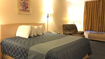 Een hotelkamer met een groot bed, een stoel, een bureau en een lamp.