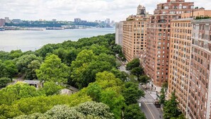 A high-rise building with a view of a river and a park with dense green trees. - Riverside Tower Hotel (New York)