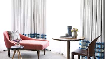 A room with a red sofa, a round table with a vase and books, and a chair.
