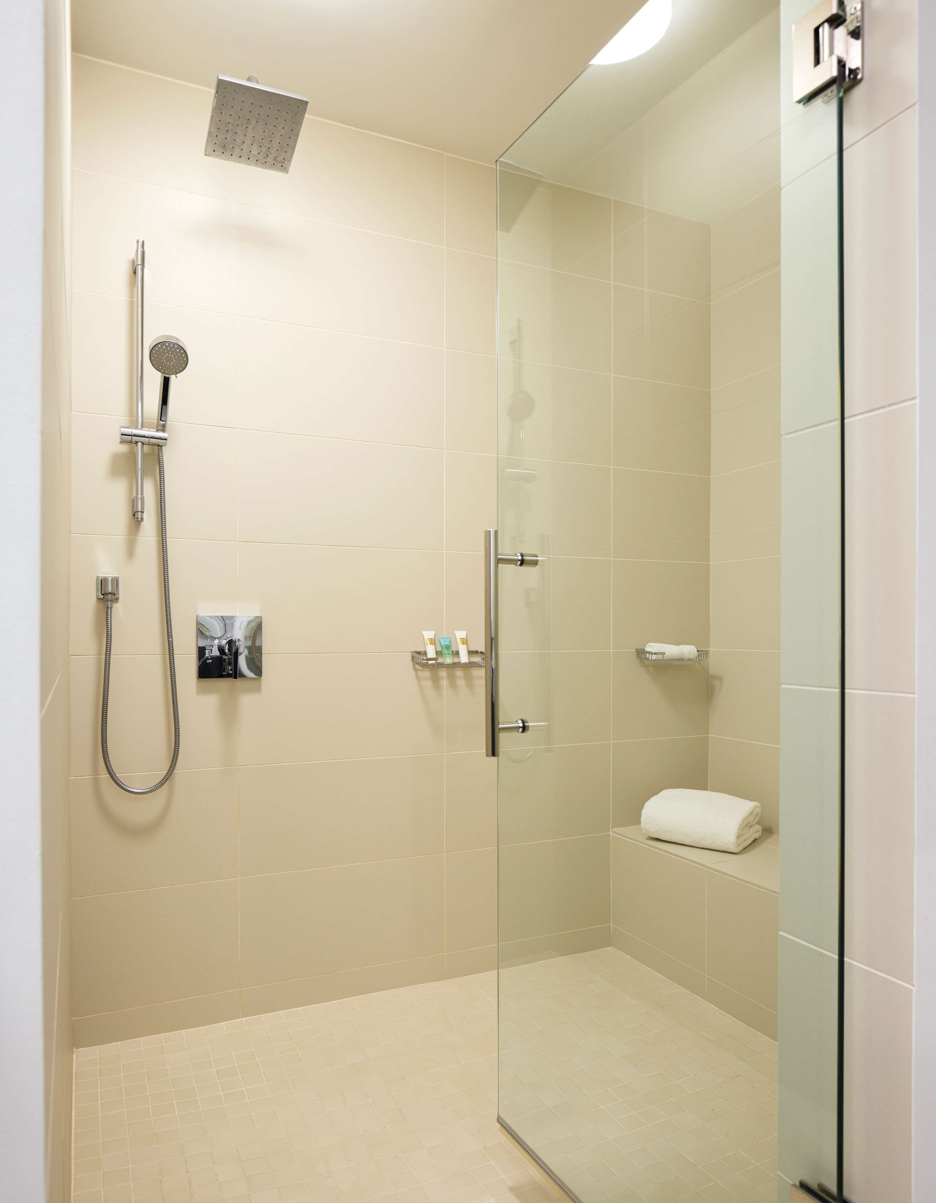 A modern shower area with a glass door, a handheld showerhead, and a wall-mounted faucet.