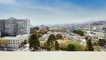 Un paisaje urbano con una mezcla de edificios modernos y antiguos, un edificio blanco destacado con techo verde, y un cielo despejado.