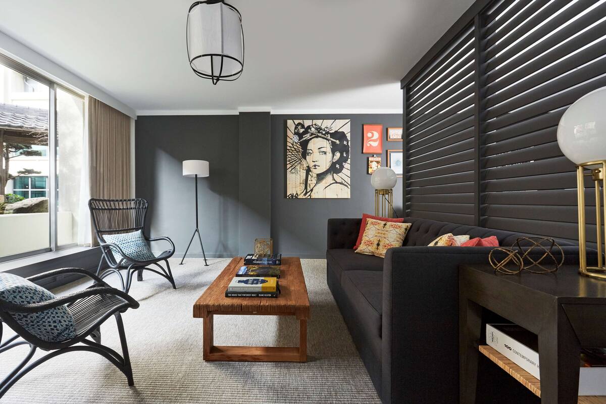 Ein modernes Wohnzimmer mit einem dunkelgrauen Sofa, einem Holztisch und schwarzen sowie weißen Sitzmöbeln mit Muster.