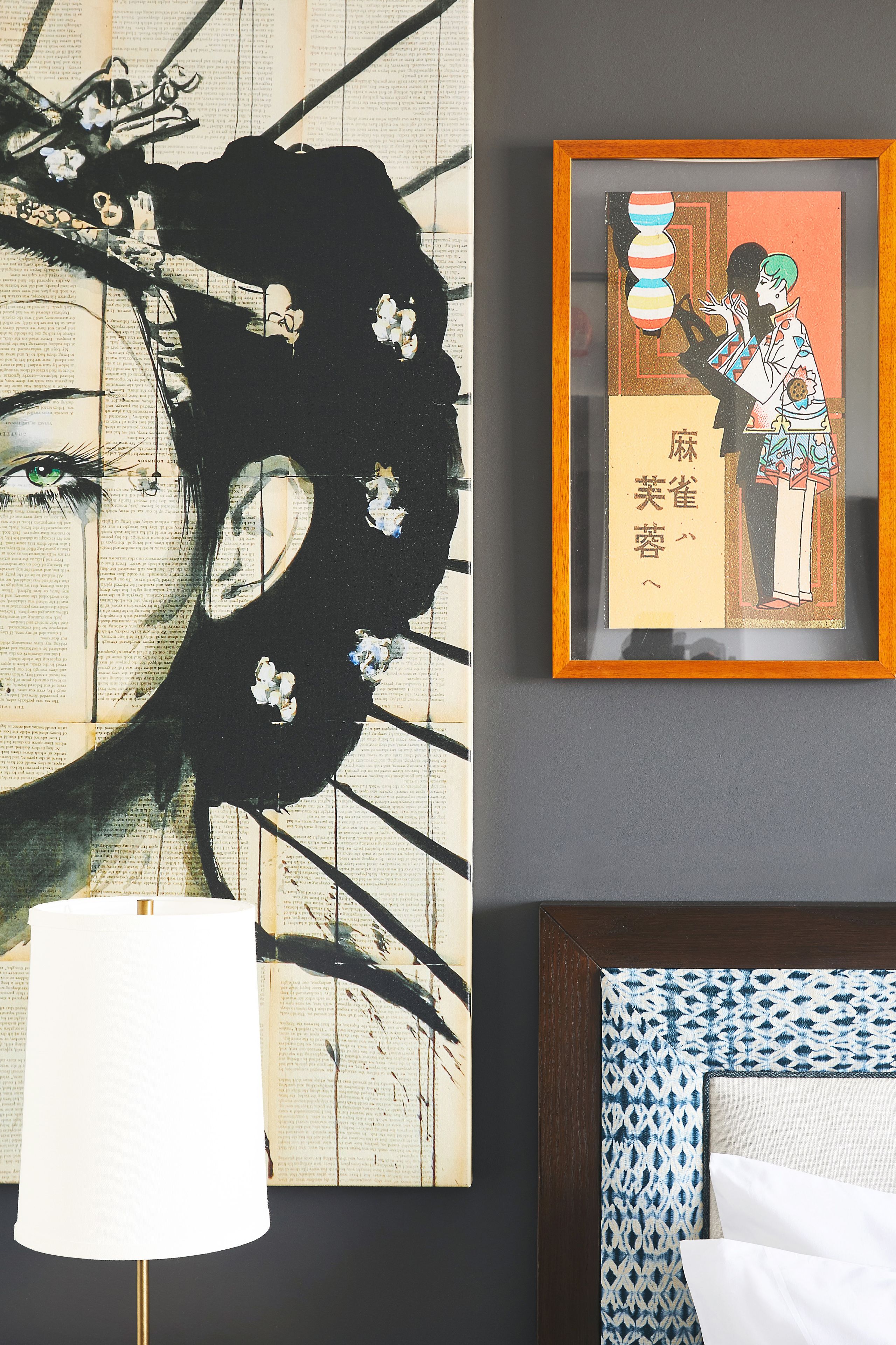 A room with a large abstract painting, a framed illustration, and a patterned headboard.
