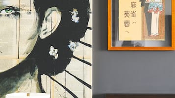 A room with a large abstract painting, a framed illustration, and a patterned headboard.