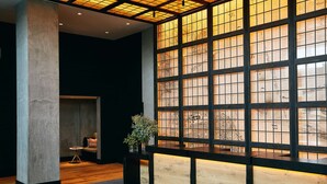 A modern interior with a large wooden panel wall, a reception desk, and a seating area with a small table and chairs. - Hotel Kabuki, part of JdV by Hyatt (San Francisco)