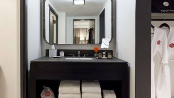 Une salle de bain moderne avec un meuble-lavabo foncé, un grand miroir et des serviettes soigneusement pliées.