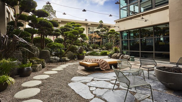 A courtyard with a stone pathway, outdoor seating, and potted plants. - Hotel Kabuki, part of JdV by Hyatt (San Francisco)
