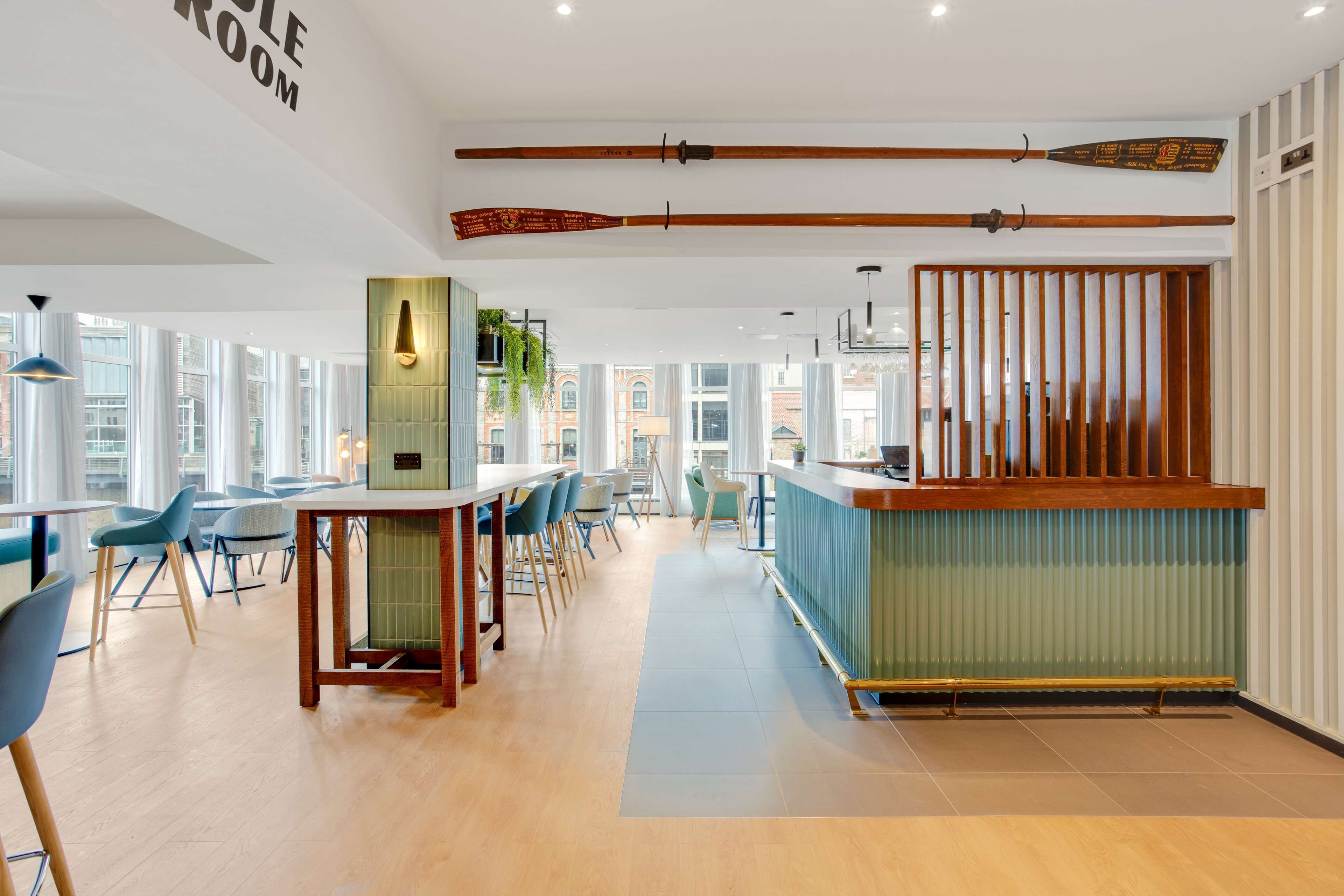 A modern restaurant with a bar area, wooden ceiling beams, and large windows.