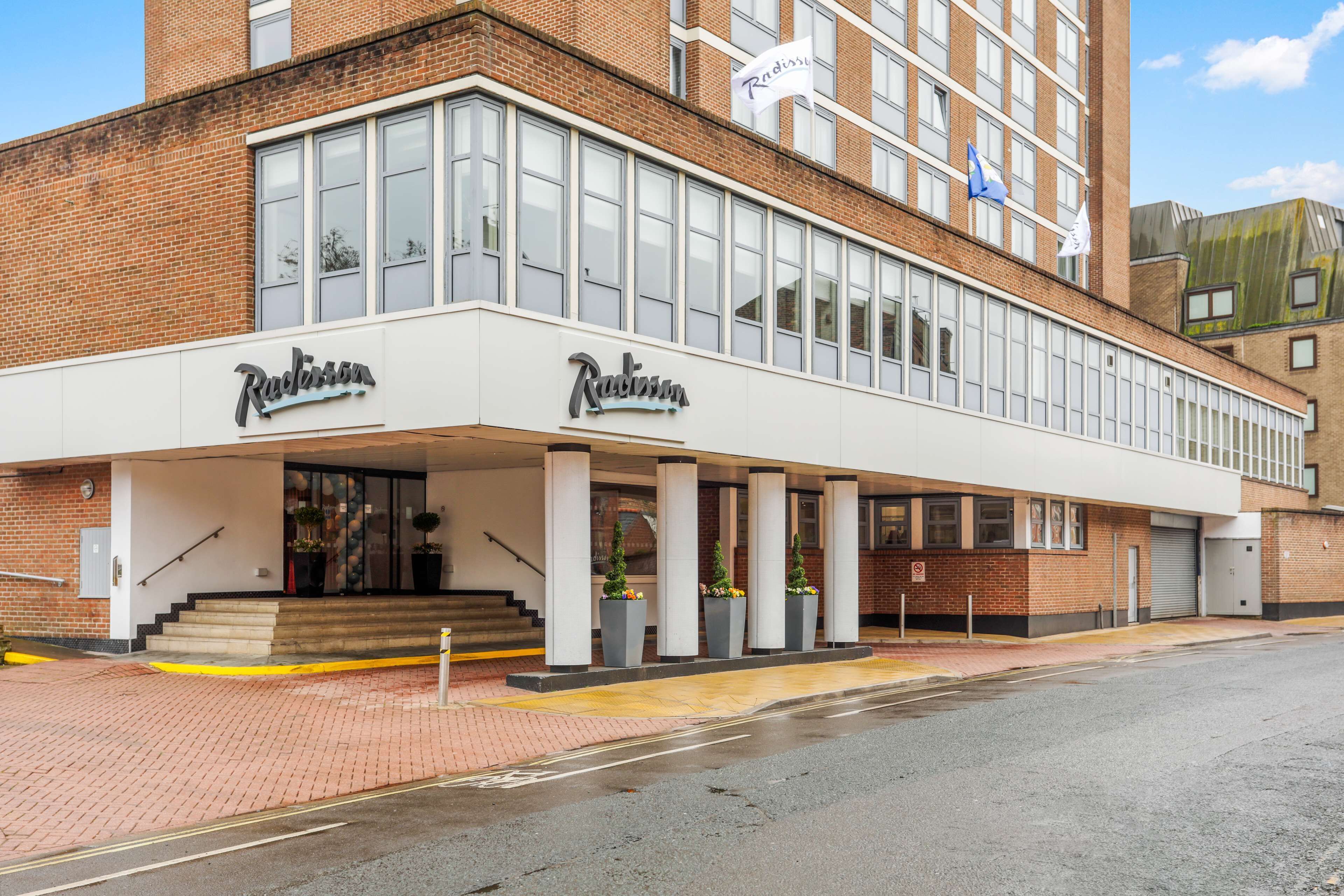 A modern building with a prominent 'Radisson' sign, featuring large windows and a brick facade.