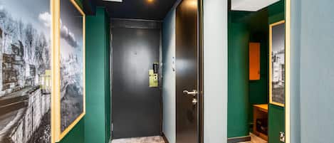 A hallway with green walls, a black door, and a framed picture on the left.