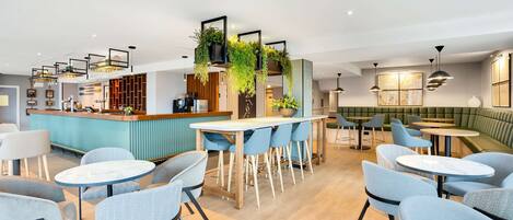 Un restaurante moderno con área de bar, arreglos de asientos y plantas decorativas.