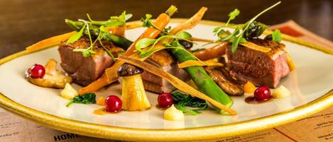 A plate of food with various vegetables and meat, placed on a table with a menu underneath.