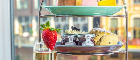 A tiered dessert stand with various pastries and a glass of champagne.