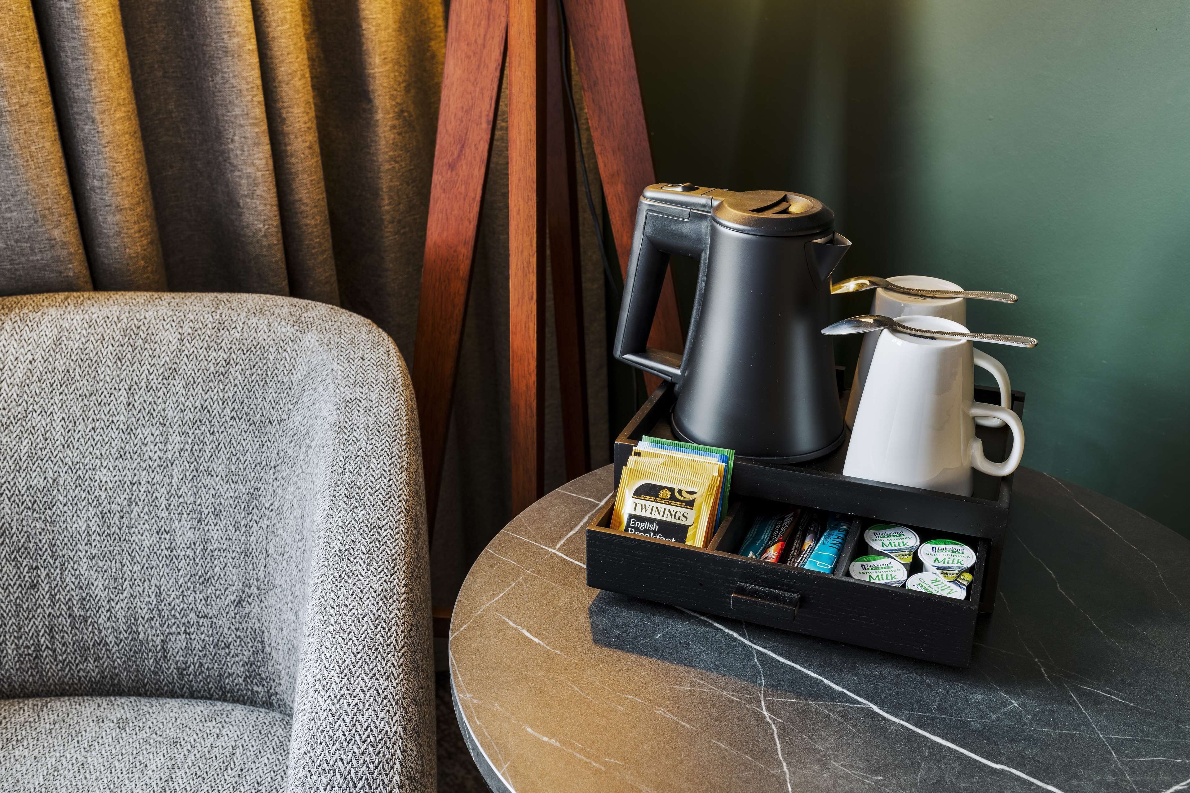 Un coin café équipé d’une machine à café, d’une tasse et d’un plateau contenant divers aliments pour le petit-déjeuner, notamment du lait et des céréales.