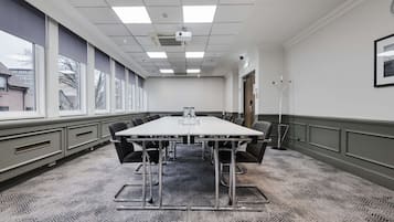 Une salle de conférence équipée d’une grande table, de chaises et d’un projecteur.